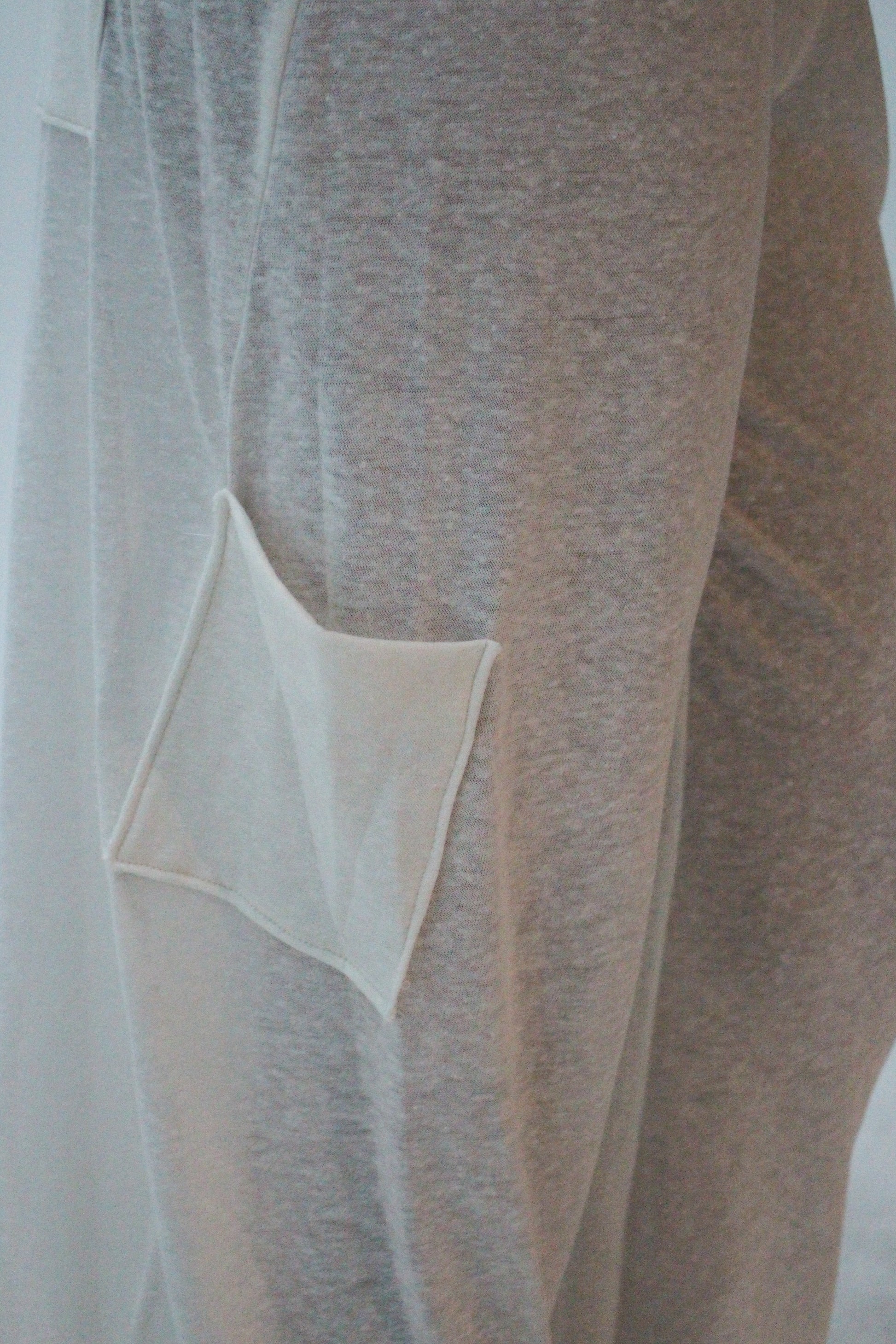 Close-up of a beige fabric with a pocket detail on a white background